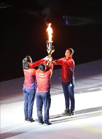 Cựu vô địch SEA Games Nguyễn Thị Tĩnh cầm đuốc từ phía ngoài SVĐ quốc gia Mỹ Đình chạy vào phía trong sân, trao lại cho bộ đôi cựu VĐV Trần Lê Quốc Toàn (cử tạ), Lê Bích Phương (karate). Ảnh: TTXVN