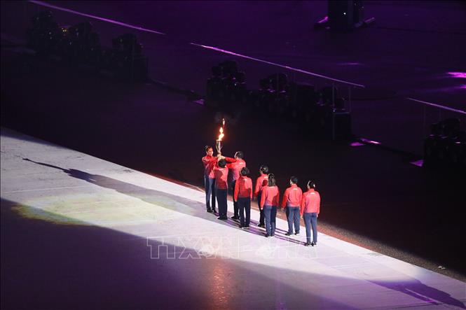 VĐV điền kinh Quách Thị Lan nhận ngọn lửa SEA Games 31 từ các VĐV. Ảnh: TTXVN