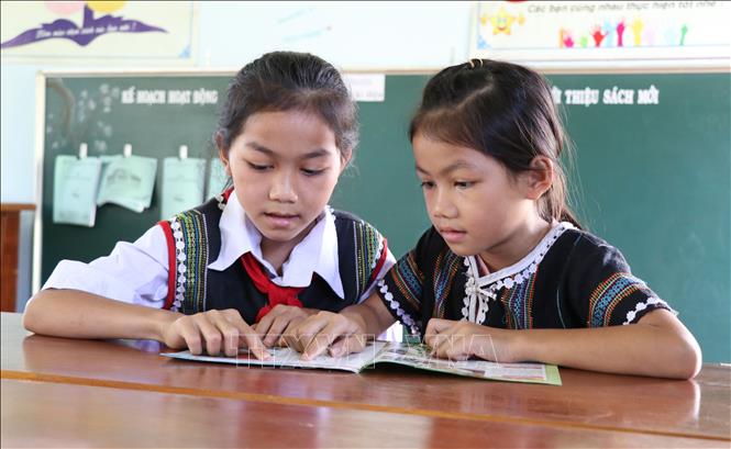 Trong ảnh: Em Chu Siu Anh Thư, lớp 5C, trường Tiểu học Ia Ka, huyện Chư Păh, Gia Lai (bên trái)  dạy em gái lớp 2 đọc chữ. Ảnh: Hồng Điệp - TTXVN