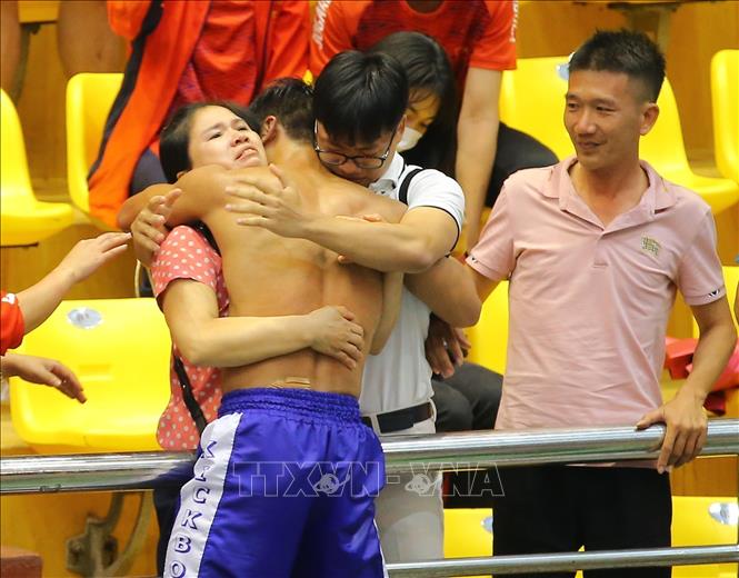 Athlete Nguyen The Huong (Vietnam-green) shares his joy with his mother and younger brother. VNA Photo