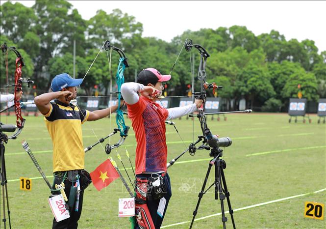 Male archers from Vietnam (in red) and Malaysia compete in the three-string bow event. VNA Photo: Vũ Sinh