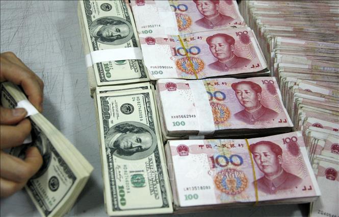 Trong ảnh: Nhân viên kiểm đồng USD và NDT tại một ngân hàng ở tỉnh An Huy, Trung Quốc. Ảnh: AFP/TTXVN