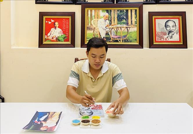 Trong ảnh: Chàng trai trẻ Khưu Tấn Bửu bên tác phẩm tranh gạo. Ảnh: Ánh Tuyết - TTXVN