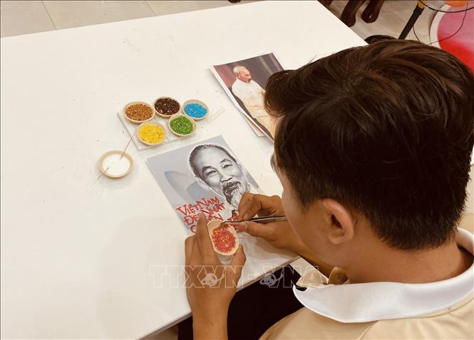 Trong ảnh: Chàng trai trẻ Khưu Tấn Bửu với tác phẩm tranh gạo. Ảnh: Ánh Tuyết - TTXVN