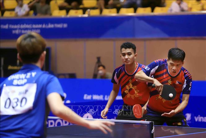 Pha phát bóng của VĐV số 21 Richard Gonzales (Philippines áo đỏ) trong trận đối đầu với VĐV số 30 Chew Zhe Yu Clarence và Poh Shao Fewg Ethan số 34 (Singapore áo xanh). Ảnh: Quý Trung – TTXVN