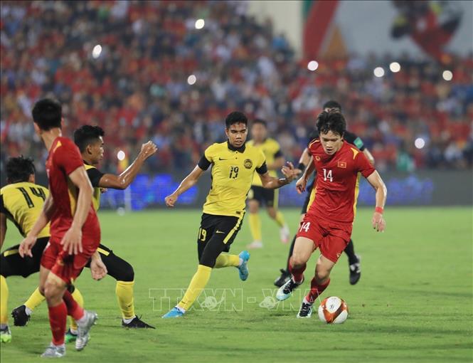 Hoang Duc (14) of Vietnam races for the ball with Malaysian rivals. VNA Photo