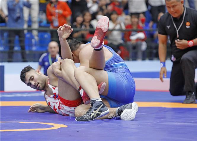 Wrestler Hoang Van Nam (blue shirt) competes against wrestler Sari Mo from Cambodia in the 97kg weight class in the men's freestyle event. VNA Photo: Trần Việt 