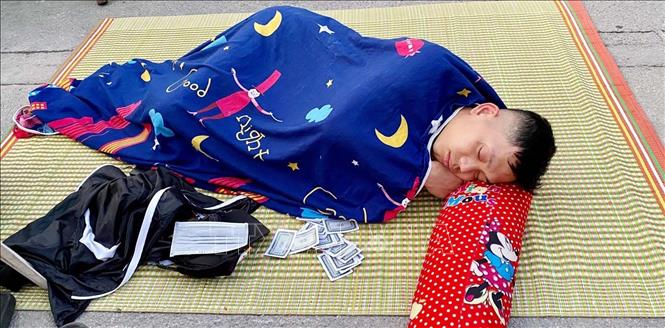 Trong ảnh: Cổ động viên có giấc ngủ ngon khi nằm chờ phát vé xem trận chung kết giữa Việt Nam-Thái Lan. Ảnh: Thanh Vân-TTXVN