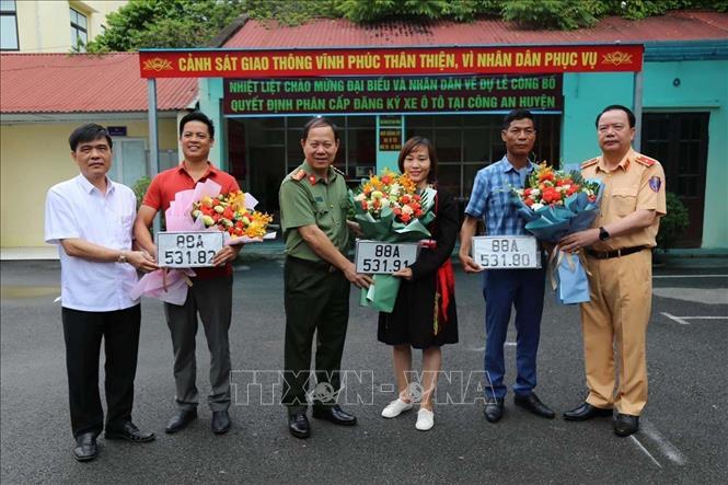 Trong ảnh: Cục trưởng Cục Cảnh sát giao thông Nguyễn Văn Trung, Giám đốc Công an tỉnh Vĩnh Phúc Đinh Ngọc Khoa, Bí thư Huyện ủy Tam Đảo Lưu Đức Long trao biển và tặng hoa cho 3 người dân đầu tiên được cấp biển số xe tại Công an huyện Tam Đảo. Ảnh: TTXVN phát