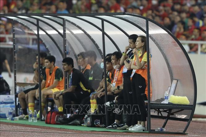 Nữ trưởng đoàn bóng đá Thái Lan Madam Pang và BHL U23 Thái Lan bên ngoài sân chăm chú theo dõi trận đấu. Ảnh: Minh Quyết - TTXVN