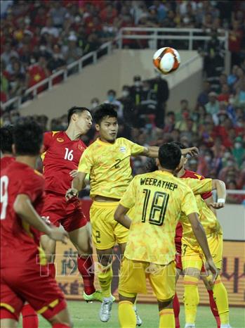 Captain of the Vietnamese team Hung Dung (16) fights for the ball in the air with Thai rivals. VNA Photo