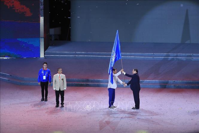 Minister of Culture, Sports and Tourism of Vietnam Nguyen Van Hung, Chairman of Southeast Asian Sports Federation, Head of the Organizing Committee of the 31st SEA Games transfers the flag to Minister of Tourism of Cambodia Thongkhon - the representative of the host country of the 32nd SEA Games. VNA Photo 