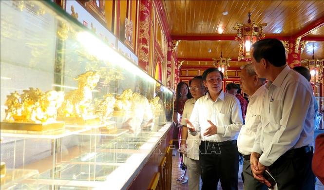 Nghệ nhân Nhân dân Trần Độ (thứ ba từ phải sang) giới thiệu về các Kim ấn cho du khách tham quan. Ảnh: Tường Vi - TTXVN