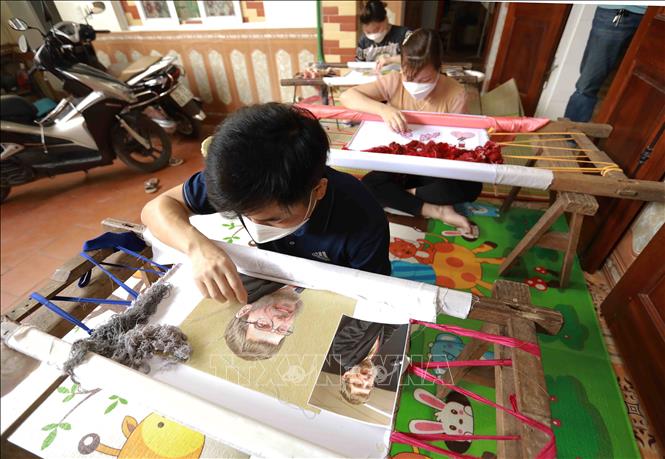 Thêu tranh chân dung tại cơ sở của Nghệ nhân thêu tranh chân dung Khúc Văn Huynh, thôn Cổ Chất, xã Dũng Tiến, huyện Thường Tín. Ảnh: Vũ Sinh - TTXVN