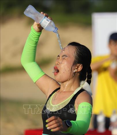 Vận động viên nữ chạy cự ly 42km tiếp nước để hạ nhiệt. Ảnh: Nguyên Linh-TTXVN