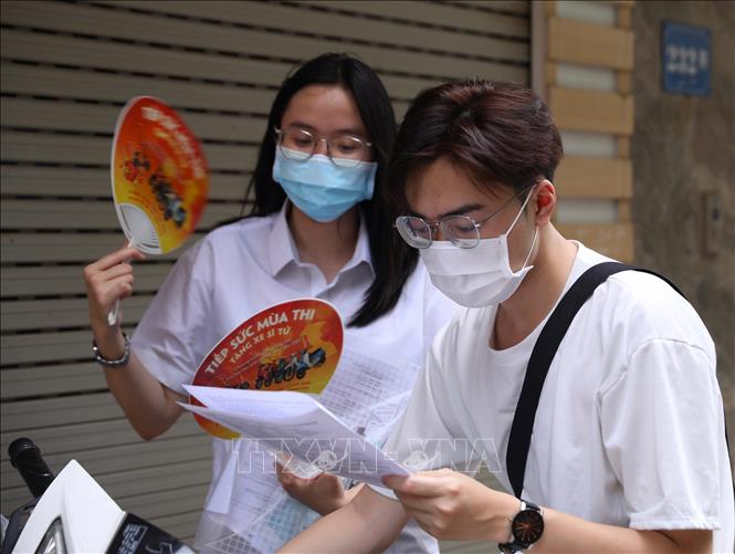 Người nhà và thí sinh tại điểm thi Trường THCS Ngô Quyền, quận Hai Bà Trưng xem đề thi sau khi kết thúc môn thi Ngoại ngữ, chiều 18/6. Ảnh: Hoàng Hiếu - TTXVN 