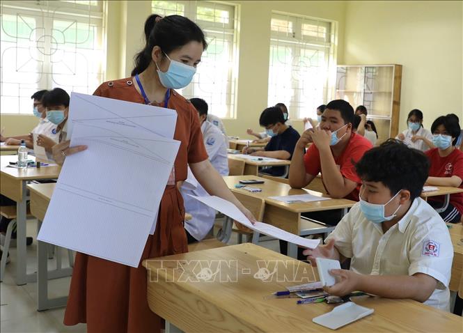 Giáo viên coi thi phát giấy cho thí sinh điểm thi Trường THCS Ngô Quyền trước giờ thi Toán. Ảnh: Hoàng Hiếu - TTXVN 