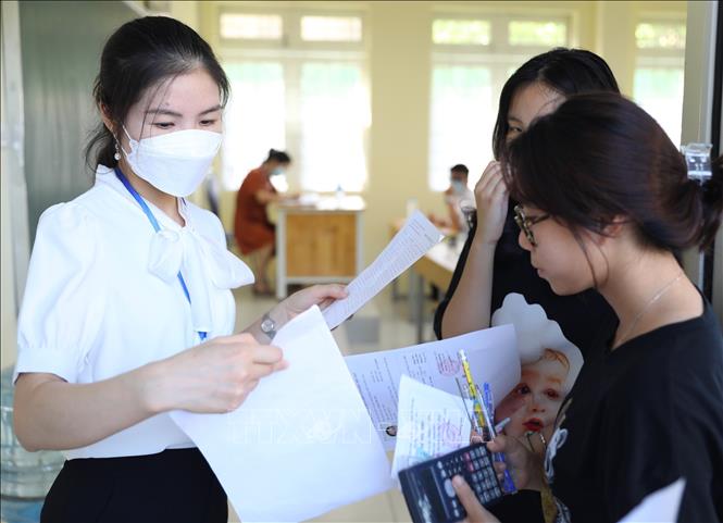 Giáo viên coi thi điểm thi Trường THCS Ngô Quyền  kiểm tra dân dạng trước khi cho thí sinh vào phòng thi. Ảnh: Hoàng Hiếu - TTXVN 
