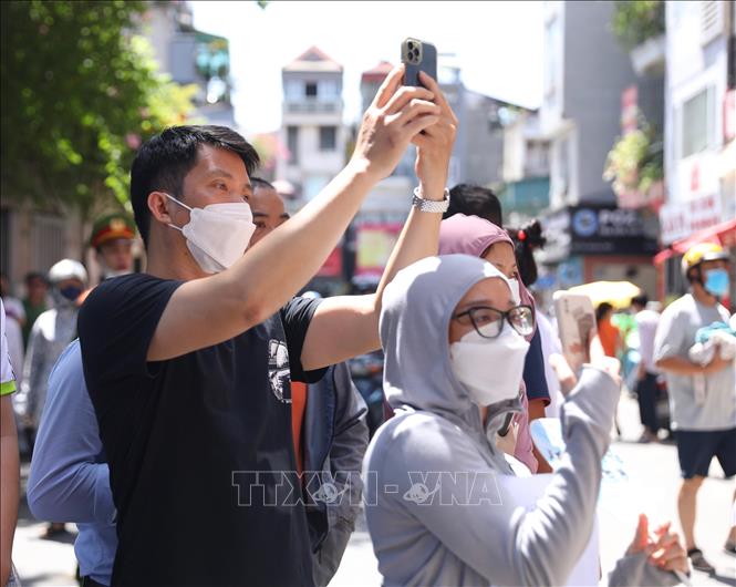 Nhiều phụ huynh lưu giữ lại khoảnh khắc thí sinh ra khỏi điểm thi Trường THPT Thăng Long. Ảnh: Hoàng Hiếu - TTXVN 