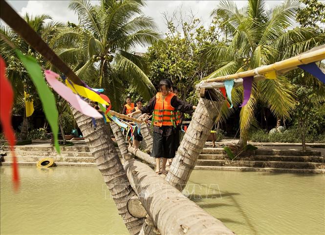 Trong ảnh: Du khách trải nghiệm đi cầu dừa trên vùng sông nước Bến Tre trong Khu du lịch sinh thái Lan Vương, ấp 2, xã Phú Nhuận, thành phố Bến Tre (Bến Tre). Ảnh: Hồng Đạt - TTXVN
