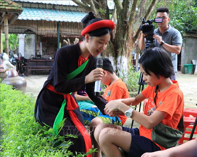 Trong ảnh: Liền chị quan họ mời trầu khán giả xem múa rối nước. Ảnh: Thanh Thương - TTXVN