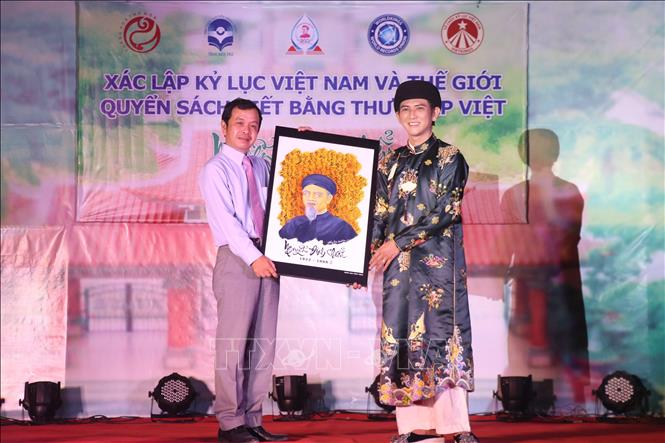 Ông Dương Tấn Phát, Giám đốc Thư viện Nguyễn Đình Chiểu tỉnh Bến Tre (bìa trái) tiếp nhận Quyển sách tượng trưng từ Nghệ nhân Vũ Đăng Học (bìa phải). Ảnh: Chương Đài - TTXVN