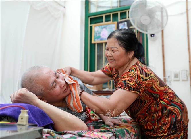 Bà Nguyễn Thị Ngạt chăm sóc tận tình chồng là ông Nguyễn Văn Cần (thương binh hạng ¼, thương tật 96%). Ảnh: Hoàng Hiếu – TTXVN