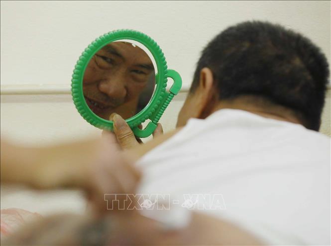Gương là vật dụng không thể thiếu để thương binh Hà Văn Lộc (thương binh 1/4, tỷ lệ thương tật 96%) theo dõi vết thương cột sống. Ảnh: Hoàng Hiếu - TTXVN