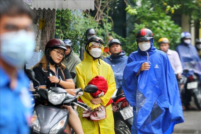 Các phụ huynh đội mưa chờ các con tại điểm thi Trường THPT Kim Liên, quận Đống Đa. Ảnh: Tuấn Đức - TTXVN