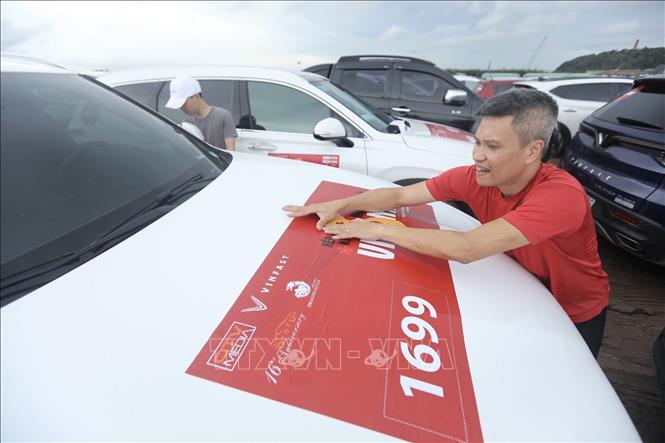 Chủ xe tranh thủ dán logo của Chương trình lên xe theo quy định. Ảnh: Minh Quyết - TTXVN