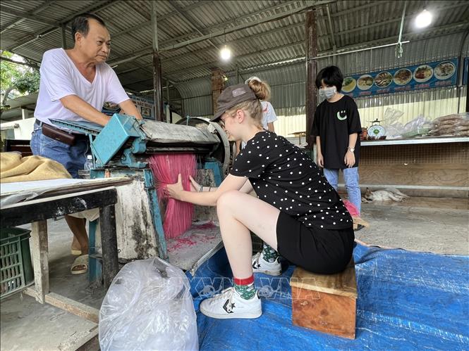 Trong ảnh: Du khách nước ngoài thích thú trải nghiệm quy trình sản xuất hủ tiếu đa sắc. Ảnh: TTXVN phát