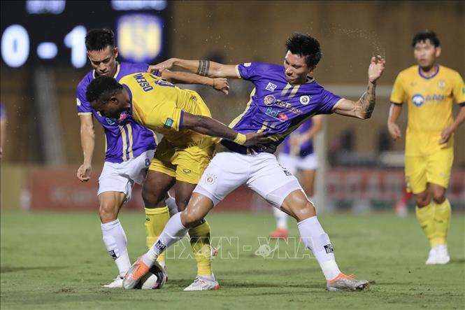 Pha tranh bóng của hậu vệ Văn Hậu (số 5, Hà Nội FC) và cầu thủ của SLNA. Ảnh: Minh Quyết - TTXVN