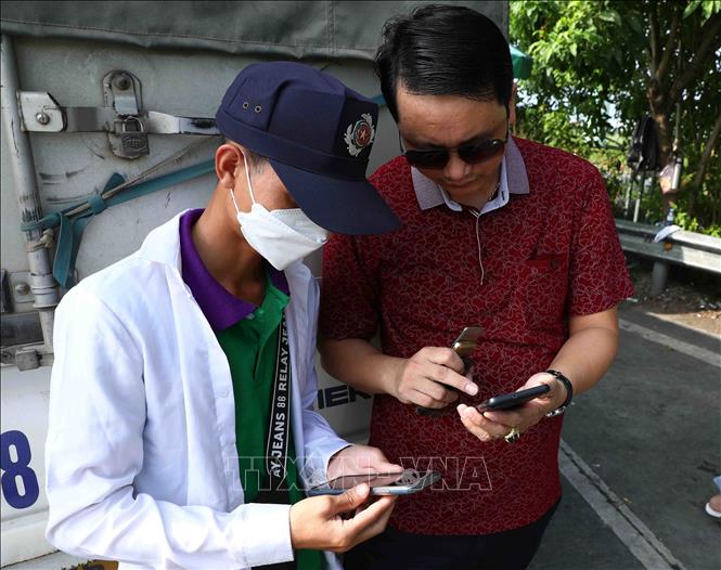 Nhân viên Công ty TNHH Thu phí tự động VETC hướng dẫn cho các chủ phương tiện dán thẻ VETC (thu phí dịch vụ sử dụng đường bộ theo hình thức điện tử tự động không dừng) tại trạm thu phí BOT Pháp Vân - Cầu Giẽ. Ảnh: Phạm Kiên - TTXVN