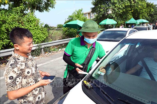 Nhân viên Công ty TNHH Thu phí tự động VETC dán thẻ VETC (thu phí dịch vụ sử dụng đường bộ theo hình thức điện tử tự động không dừng) cho các phương tiện khi đi qua trạm thu phí BOT Pháp Vân - Cầu Giẽ. Ảnh: Phạm Kiên - TTXVN