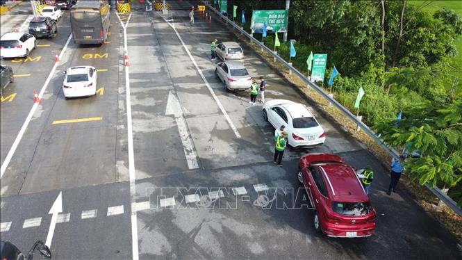 Nhân viên Công ty TNHH Thu phí tự động VETC hướng dẫn cho các chủ phương tiện dán thẻ VETC (thu phí dịch vụ sử dụng đường bộ theo hình thức điện tử tự động không dừng) tại trạm thu phí BOT Nội Bài - Lào Cai. Ảnh: TTXVN phát