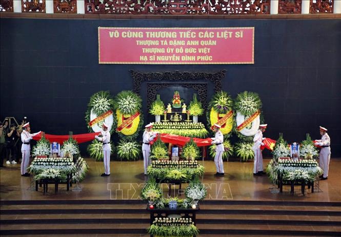 Nghi thức phủ cờ Tổ quốc lên linh cữu 3 liệt sĩ. Ảnh: Phạm Kiên - TTXVN