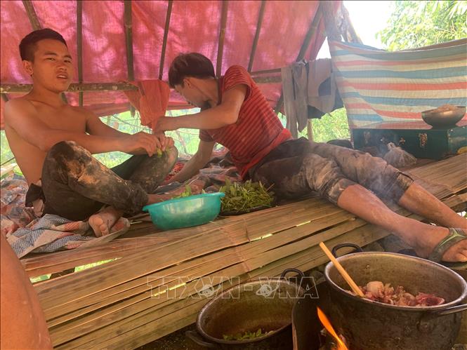 Hai thanh niên nấu cơm trưa trong điểm khai thác vàng Nậm Khá, xã Mù Cả, huyện Mường Tè, tỉnh Lai Châu. Ảnh: Nhóm PV TTXVN tại Lai Châu