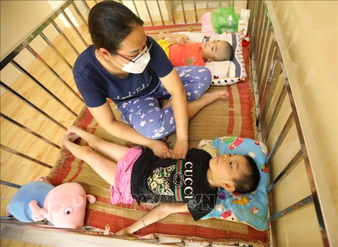 Dì nuôi, mẹ nuôi luôn tận tâm chăm sóc 7 cháu khuyết tật nặng và đặc biệt nặng thuộc gia đình Vành Khuyên. Ảnh: Hoàng Hiếu - TTXVN 