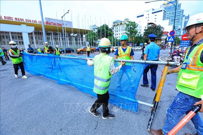 Thanh tra giao thông và công nhân dựng rào chắn phân luồng, đoạn phố Trần Hưng Đạo. Ảnh: Tuấn Anh - TTXVN