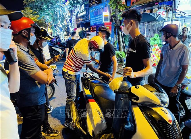 Tại đường Trần Nhật Duật (đoạn lối lên cầu Long Biên), tổ công tác Y1/141 đã phát và xử lý hai thanh niên không đội mũ bảo hiểm, chở theo bình bóng cười kèm nhiều vỏ bóng. Ảnh: Phạm Kiên - TTXVN