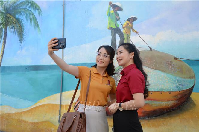 Trong ảnh: Khách du lịch chụp ảnh lưu niệm tại Đường tranh bích họa phường Mân Thái. Ảnh: Văn Dũng - TTXVN
