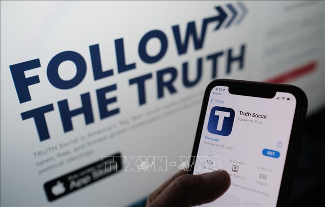 Trong ảnh: Biểu tượng mạng xã hội Truth Social trên màn hình điện thoại và trang web của ứng dụng này trên màn hình máy tính. Ảnh: AFP/TTXVN