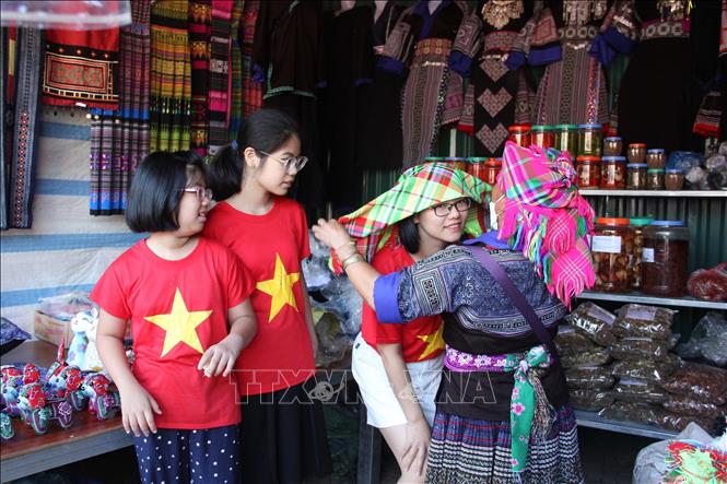 Du khách thích thú khi được thử các trang phục truyền thống của đồng bào Mông tại chợ phiên Mù Cang Chải. Ảnh: Việt Dũng - TTXVN
