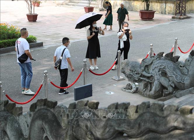 Các du khách Châu Á dừng trước điện Kính Thiên, một điểm nhấn khi tham quan Hoàng thành Thăng Long. Ảnh: Thanh Tùng - TTXVN