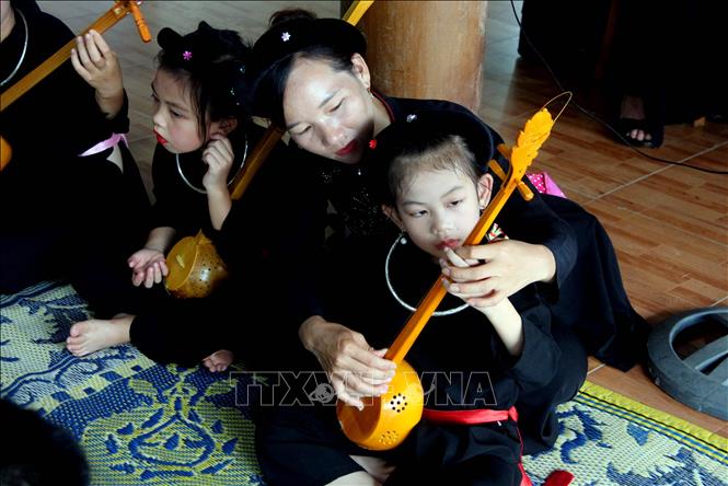 Chị Đàm Thanh Hiền, Chủ nhiệm câu lạc bộ hát Then - đàn Tính cội nguồn xã Trung Yên (Sơn Dương, Tuyên Quang) hướng dẫn các cháu nhỏ cách chơi đàn Tính. Ảnh: Quang Cường – TTXVN