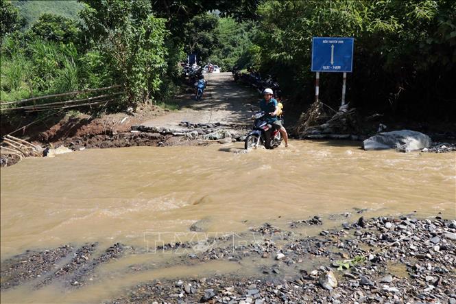 Trong ảnh: Người dân phải đi qua suối để đến UBND xã và khám bệnh tại trạm y tế. Ảnh: Hữu Quyết - TTXVN