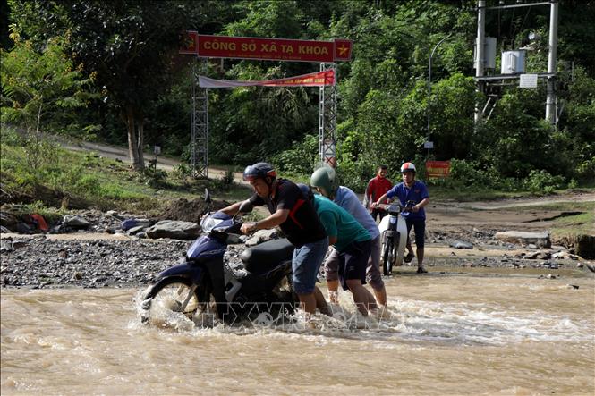 Trong ảnh: Do mưa lũ, nước suối dâng cao khiến người dân rất vất vả khi muốn đến giao dịch tại UBND xã và khám bệnh tại trạm y tế. Ảnh: Hữu Quyết - TTXVN