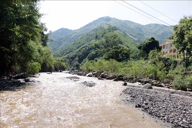 Trong ảnh: Do mưa lũ, nước suối dâng cao khiến người dân rất vất vả khi muốn đến giao dịch tại UBND xã và khám bệnh tại trạm y tế.  Ảnh: Hữu Quyết - TTXVN
