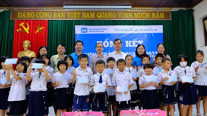 Trong ảnh: Giáo dục và Đào tạo đã tặng 20 suất quà, mỗi suất trị giá 500.000 đồng và cùng chung vui với học sinh của làng. Ảnh: Bích Huệ - TTXVN