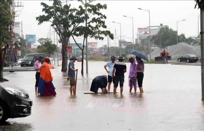 Trong ảnh: Người dân khơi thông dòng chảy ở một số tuyến đường ngập sâu tại thành phố Vinh (Nghệ An). Ảnh: Tá Chuyên - TTXVN 